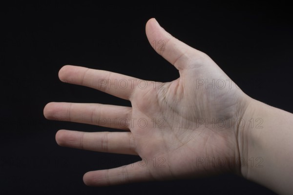 Five fingers of a child hand partly seen in black background