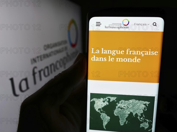 Stuttgart, Germany, 06-26-2024: Person holding cellphone with webpage of Organisation internationale de la Francophonie in front of logo. Focus on center of phone display, Europe