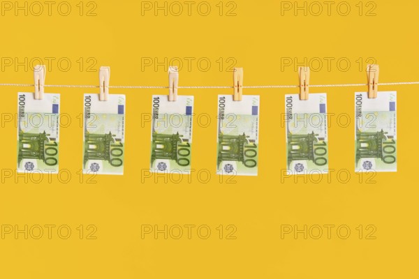 Money laundering, euro banknotes hanging on rope over yellow studio background. Finance, corruption, criminal activity concept