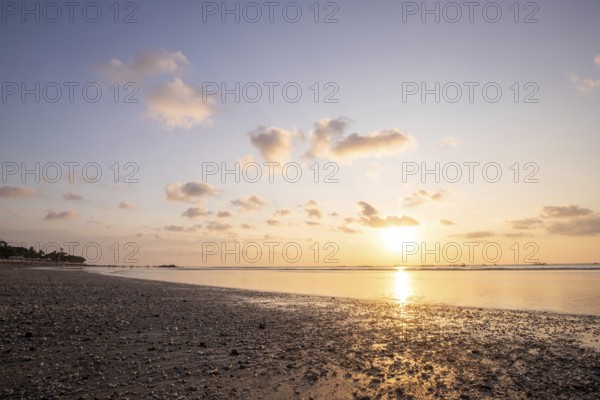 Dreamlike sunset on the dream beach of Kuta, small waves sunset over the sea and the reflection of the sky in the shallow water. Topical Bali in Indonesia