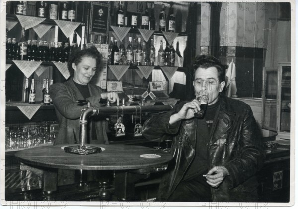 Pub, landlady, man drinking beer at the bar, smoking, 1960s, Germany, Europe