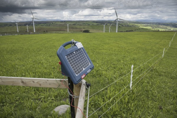 Solar powered electric fencing in pasture, with wind turbines in the background, Adfa, Newtown, Powys, Wales