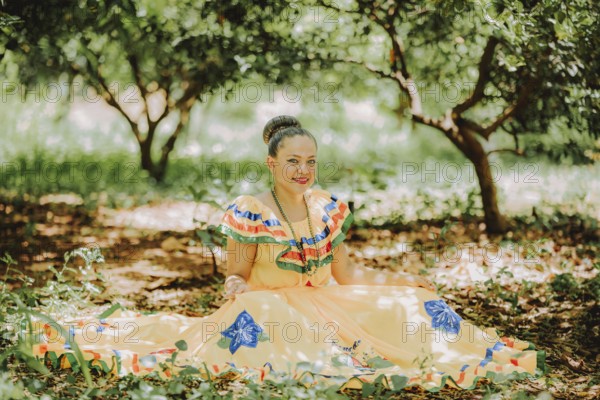 Happy girl in national folk costume sitting on the grass