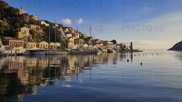 Picturesque harbour with reflecting buildings in the water. Atmospheric sky at sunset, Symi town, Symi, Dodecanese, Greek Islands, Greece, Europe