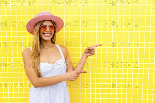 Fashionable woman indicating empty space on vibrant yellow background, ideal for showcasing products or messages