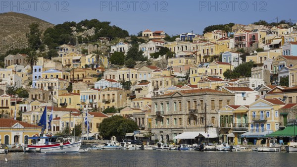 Colourful village stretches over hills with boats on the water and exudes Mediterranean serenity, Symi Town, Symi, Dodecanese, Greek Islands, Greece, Europe