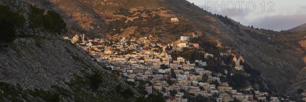 Town in the mountains in the warm morning light, Symi town, Symi, Dodecanese, Greek Islands, Greece, Europe