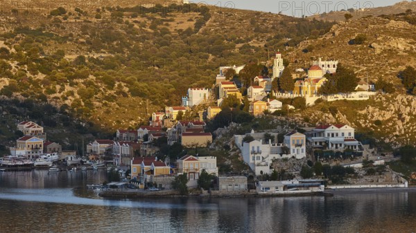 Small coastal town, surrounded by vegetation, reflected in the water, Symi Town, Symi, Dodecanese, Greek Islands, Greece, Europe