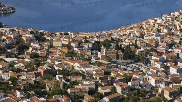 Dense cluster of houses overlooking the sea beyond, Symi Town, Symi, Dodecanese, Greek Islands, Greece, Europe