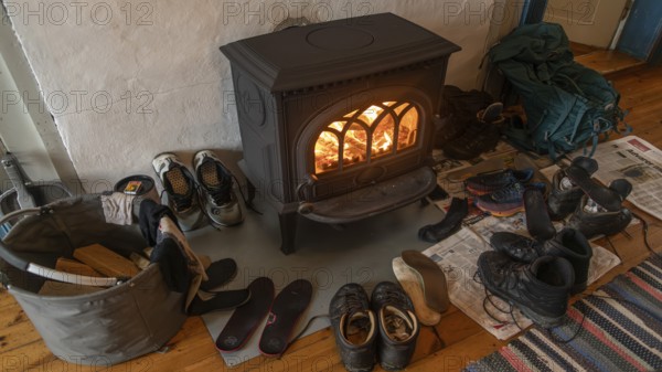 Drying wet hiking boots in front of a burning wood-burning stove, Fokstugu farm, Fjellstue, pilgrims' accommodation, mountain hut, Olavsweg, Olavsleden or Pilgrimsleden, Dovrefjell-Sunndalsfjella National Park, Norway, Europe