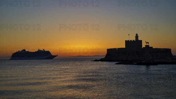 Cruise ship passing a fortress, calm, warm sky, sunrise, dawn, Fort of Saint Nikolaos, Mandraki harbour, Rhodes town, Rhodes, Dodecanese, Greek Islands, Greece, Europe