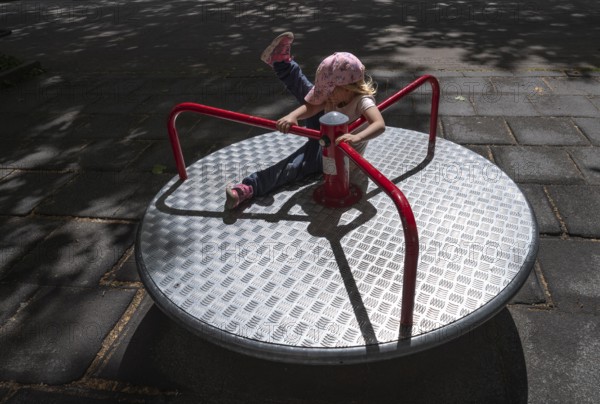 Outdoor shot, little girl, 3 years old, blonde, playing on a merry-go-round, children's playground, playground, Stuttgart, Baden-Württemberg, Germany, Europe