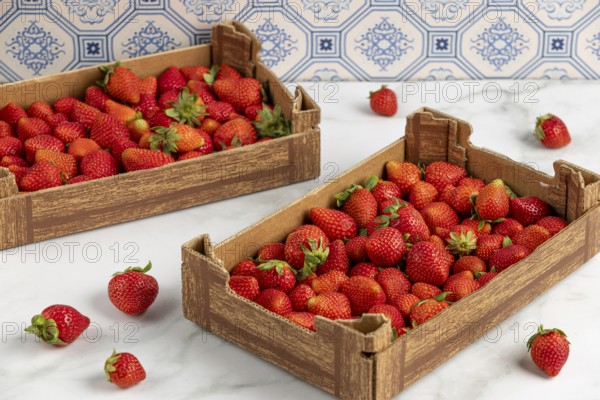 Two full cartons of vibrant red strawberries, blue pattern in the background