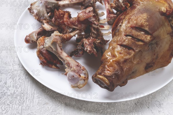 Roast pork head, with remnants of bones and meat, on a white platter, no people, close-up