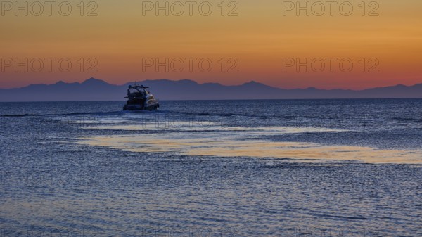Lonely boat on the sea with mountains in the background, sunrise, dawn, Fort of Saint Nikolaos, Mandraki harbour, Rhodes town, Rhodes, Dodecanese, Greek Islands, Greece, Europe