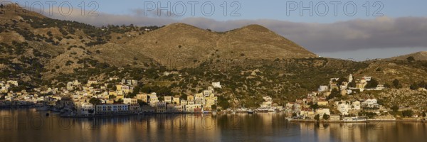 Island with houses and mountains in the background, calm water, atmospheric landscape, Symi town, Symi, Dodecanese, Greek Islands, Greece, Europe