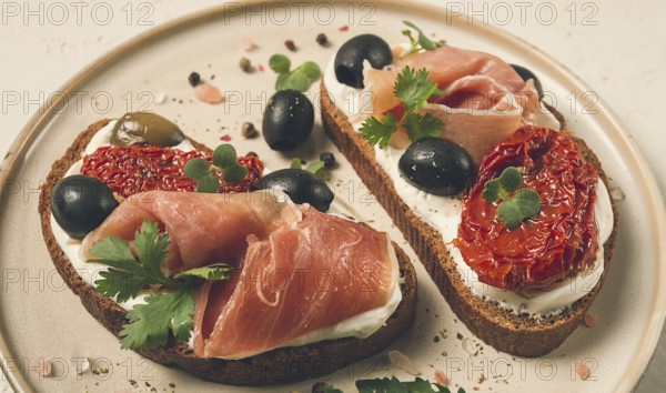 Sandwiches with cheese and prosciutto, dried tomatoes and olives, breakfast on a plate