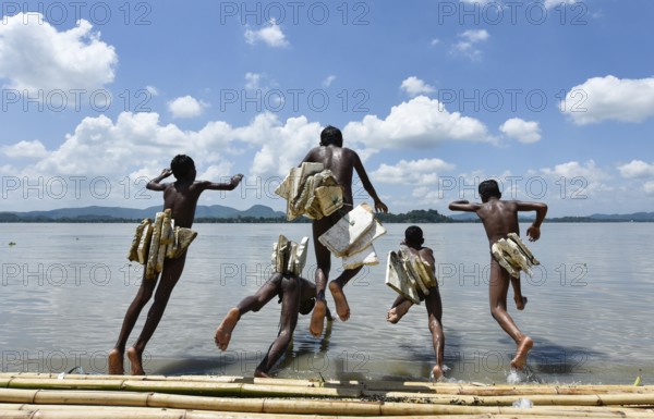 Boys jump in the Brahmaputra river wearing polystyrene sheets to keep themself float in the water during a hot summer day, in Guwahati, Assam, India on 22 Jun 2019