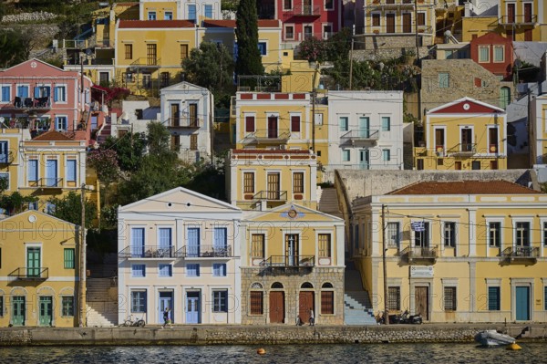 Colourful houses along a water with reflection, Symi Town, Symi, Dodecanese, Greek Islands, Greece, Europe
