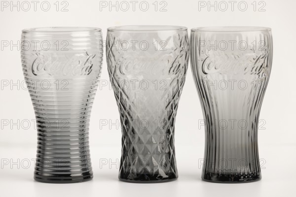 Three stylish, differently designed cola glasses in transparent and black tones