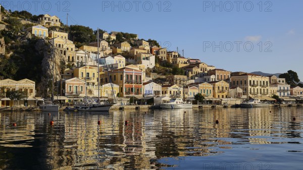 Coastal town with colourful houses on the bay, boats in the calm water, Symi Town, Symi, Dodecanese, Greek Islands, Greece, Europe