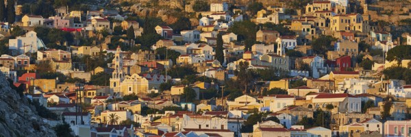 Houses standing close together in warm morning light on a hill, Symi town, Symi, Dodecanese, Greek Islands, Greece, Europe