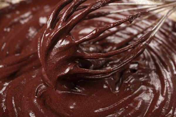 A bowl of chocolate dough, a whisk for whipping, baking, structure and consistency, homemade, top view, no people