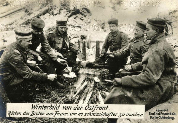 Winter picture from the eastern front. Roasting bread by the fire to make it more flavourful, 1914 - 1918, World War I, reproduction of a war postcard