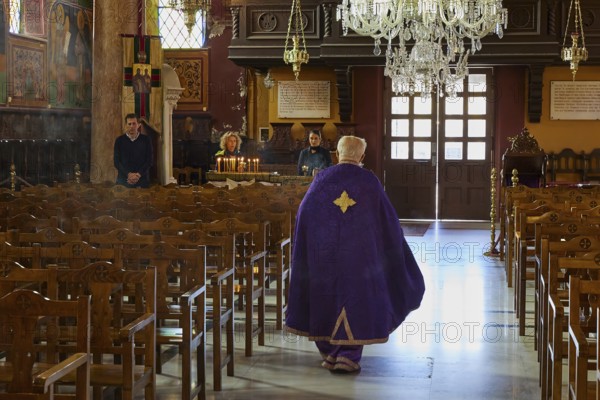 A priest in a purple robe walks through the empty pews of a church, Church of the Annunciation of the Blessed Virgin Mary, Rhodes Town, Greece, Orthodox Church, Dodecanese, Greek Islands, Rhodes Town, Holy Week, Rhodes, Europe
