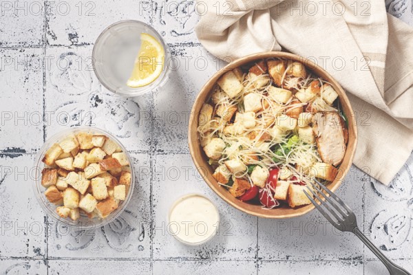 Caesar salad in a paper container, take it on the way, with sauce and croutons, on the table, snack, natural light, no people