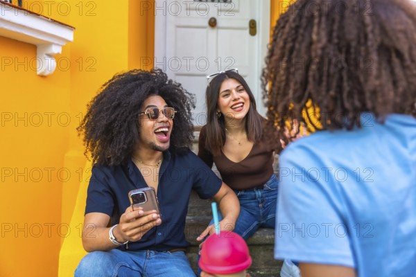 Three cheerful friends enjoying a lively conversation and refreshments while sitting on vibrant steps, creating a joyful and social atmosphere