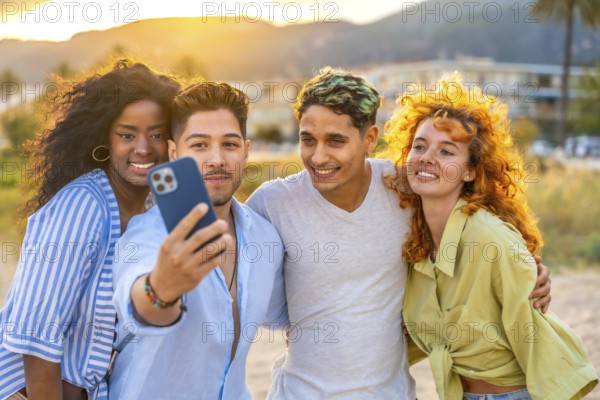 Four cheerful young friends of diverse backgrounds capturing a joyful selfie at sunset on a stunning beach, creating lasting memories