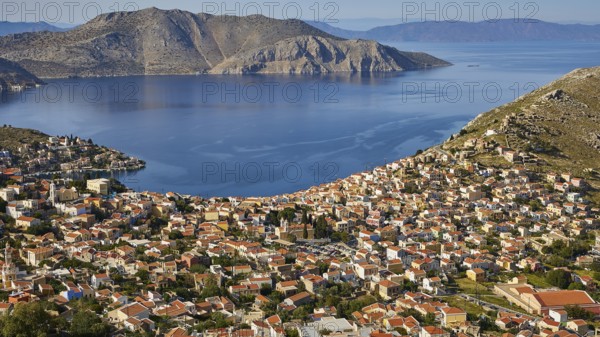 View of a town surrounded by mountains and a calm sea coast, Symi Town, Symi, Dodecanese, Greek Islands, Greece, Europe