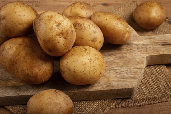 Raw potatoes, scattered on a chopping board, close-up, no people