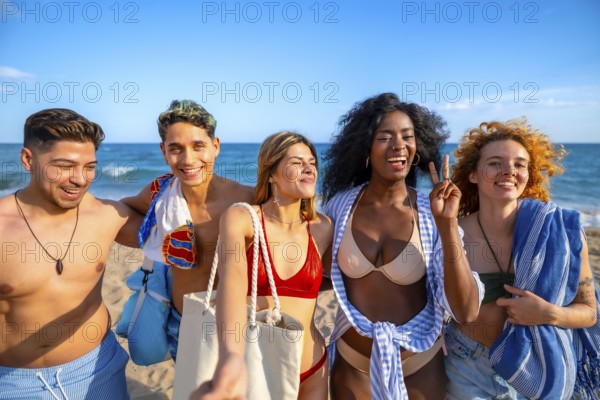Group of multi ethnic friends enjoying a sunny day at the beach, capturing joyful moments while taking selfies during their summer vacation