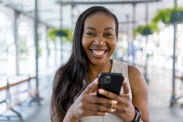 Smiling businesswoman using mobile phone in bright, modern office space, enjoying convenient communication and connectivity