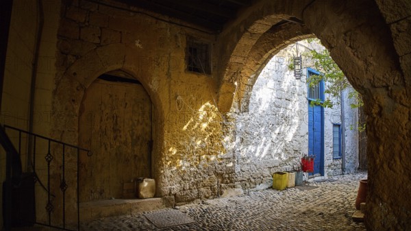 Weathered stone arcade with rays of light falling through an old archway, Rhodes Old Town, Rhodes, Dodecanese, Greek Islands, Greece, Europe