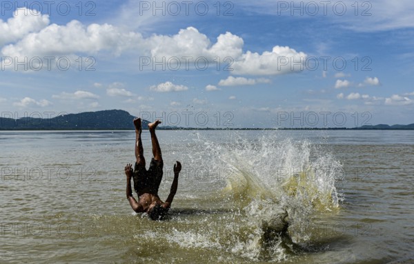 Boys jump in the Brahmaputra river during an a hot summer day in Guwahati, india on July 11, 2022