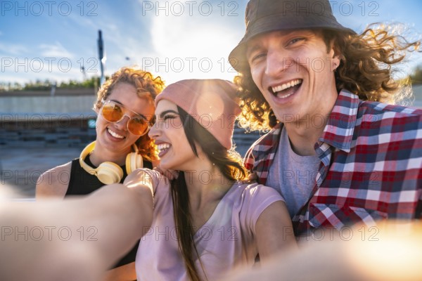 Three cheerful young friends taking a selfie outdoors, soaking up the sun and enjoying a vibrant day in the city together