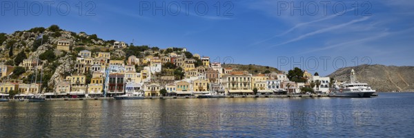 Coastal town with picturesque harbour, colourful houses and calm sea under a blue sky, Symi Town, Symi, Dodecanese, Greek Islands, Greece, Europe