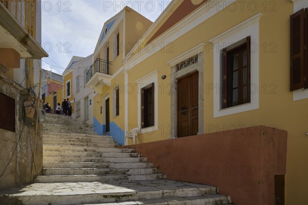 Narrow stairway flanked by yellow houses, in the sunshine, Symi Town, Symi, Dodecanese, Greek Islands, Greece, Europe