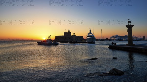 Sunrise in the harbour with boats and an impressive fortress silhouette, Sunrise, Dawn, Fort of Saint Nikolaos, Mandraki Harbour, Rhodes Town, Rhodes, Dodecanese, Greek Islands, Greece, Europe