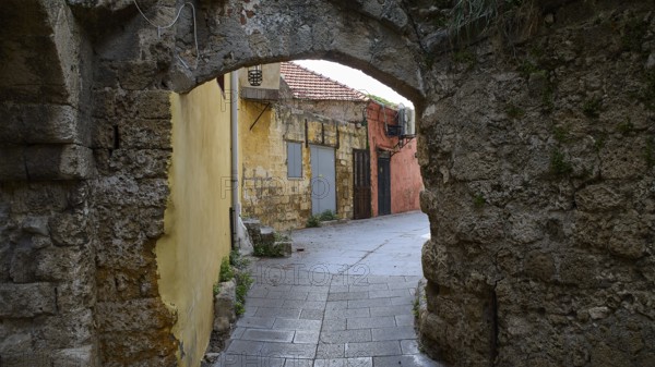 Abandoned corridor with yellow and red walls and stone arches, Rhodes Old Town, Rhodes, Dodecanese, Greek Islands, Greece, Europe