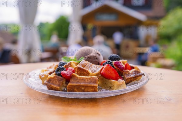 Fresh waffles with berries and ice cream on a table in front of a cosy outdoor café, Cafehäusle Calw, Black Forest, Germany, Europe