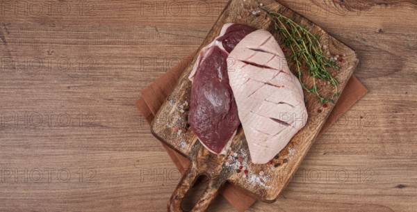 Fresh raw duck breasts, on a wooden chopping board, with herbs and spices, no people