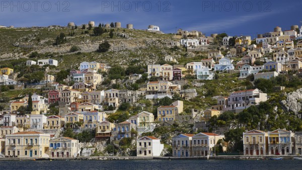Village full of colourful houses on a hill overlooking the coast and the sea, Symi Town, Symi, Dodecanese, Greek Islands, Greece, Europe
