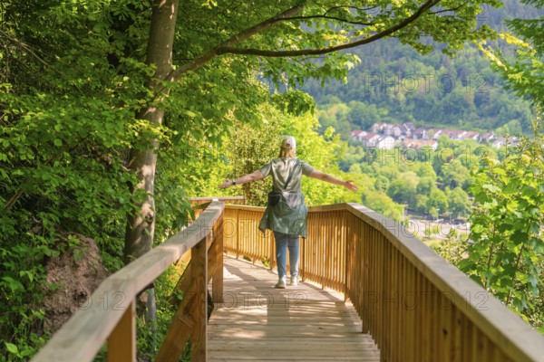 A person walks on a wooden path with outstretched arms through nature, Panorama Holzsteg, Calw, Black Forest, Germany, Europe