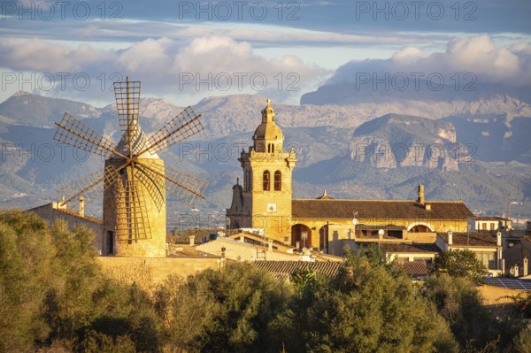 Village with windmill and church in front of mountains under a cloudy sky, Algaida, Majorca, Spain, Europe