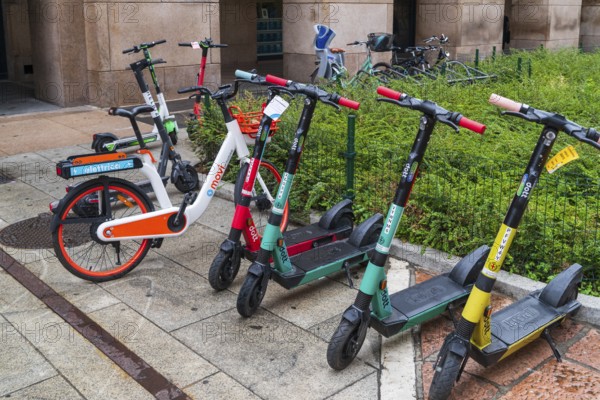 MILAN, ITALY, AUGUST 4, 2021: colorful rental scooters and bicycles on a sidewalk in the city center of Milan