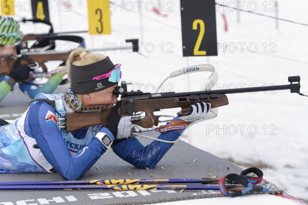 Kamchatka sportswoman biathlete Petrunova Kseniya rifle shooting in prone position. Biathlete in shooting range of Open regional youth biathlon competitions East Cup. Kamchatka, Russia, Apr 12, 2019, Europe
